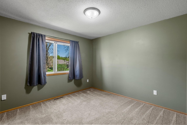 carpeted empty room with a textured ceiling and baseboards