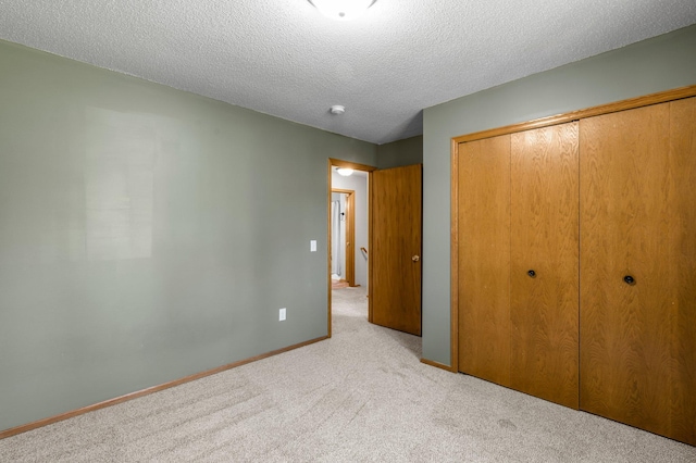 unfurnished bedroom with carpet floors, a closet, a textured ceiling, and baseboards