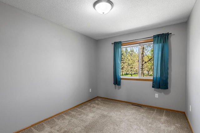 carpeted spare room featuring baseboards and a textured ceiling