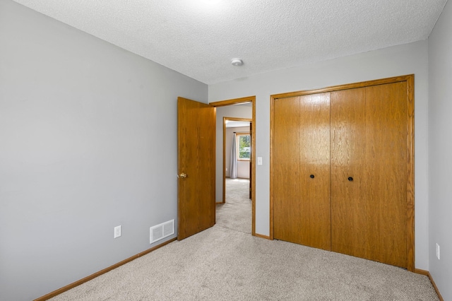 unfurnished bedroom with carpet floors, a closet, baseboards, and a textured ceiling