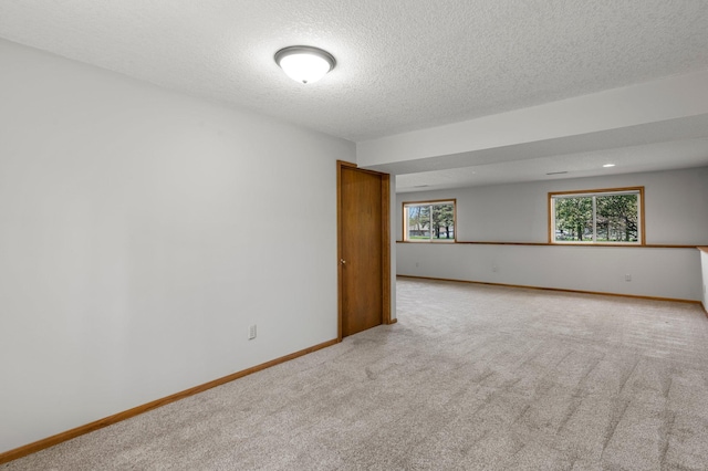 carpeted spare room featuring a textured ceiling and baseboards