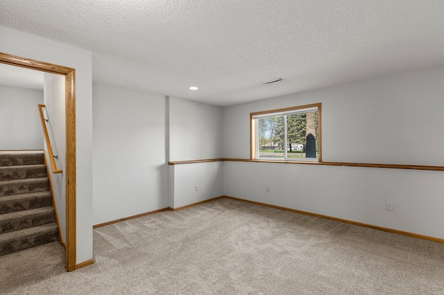 below grade area with light colored carpet, baseboards, stairway, a textured ceiling, and recessed lighting