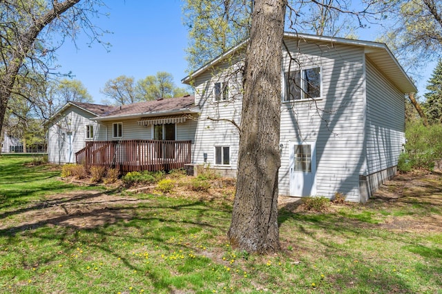 back of property with a wooden deck and a lawn