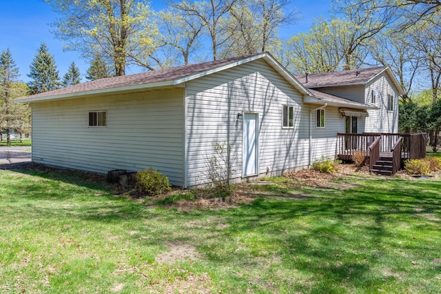 view of home's exterior with a wooden deck, a yard, and a shingled roof