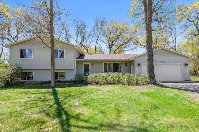 split level home featuring an attached garage, asphalt driveway, and a front lawn