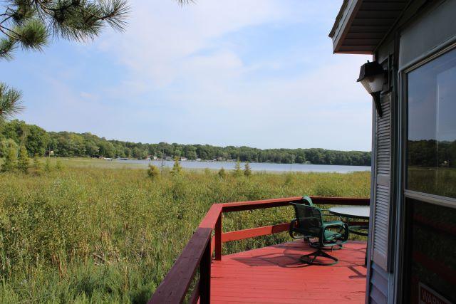 deck with a water view and a wooded view