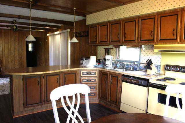 kitchen with a sink, ventilation hood, white appliances, light countertops, and a peninsula