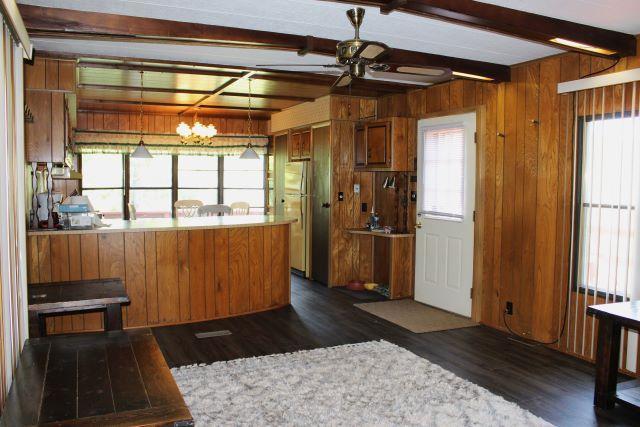 kitchen with brown cabinetry, freestanding refrigerator, beamed ceiling, dark wood-type flooring, and ceiling fan with notable chandelier