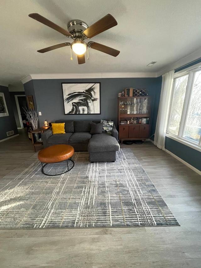 living room featuring baseboards, a ceiling fan, crown molding, and wood finished floors