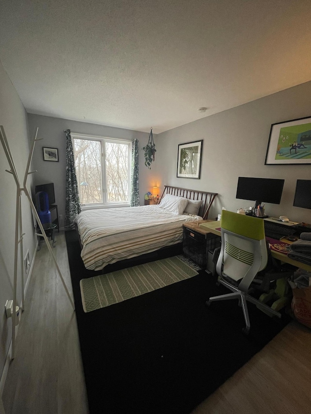 bedroom with a textured ceiling and wood finished floors