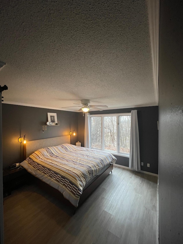 bedroom with baseboards, ceiling fan, a textured ceiling, and wood finished floors