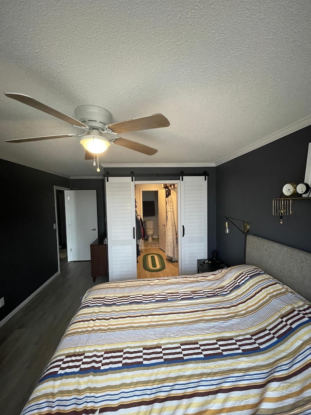 bedroom featuring ornamental molding, ceiling fan, a barn door, and wood finished floors