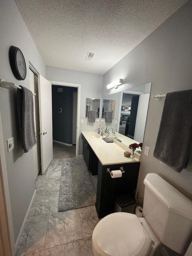 bathroom featuring visible vents, baseboards, vanity, toilet, and marble finish floor
