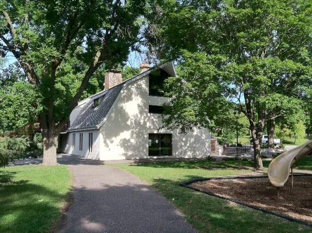 view of home's exterior with a lawn, a gambrel roof, stucco siding, and a chimney