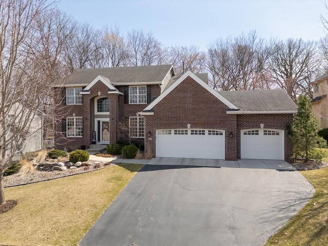 view of front of house featuring a shingled roof, an attached garage, a front lawn, brick siding, and aphalt driveway
