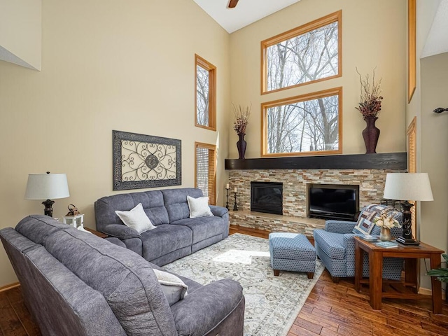 living room with a fireplace, high vaulted ceiling, baseboards, and hardwood / wood-style floors