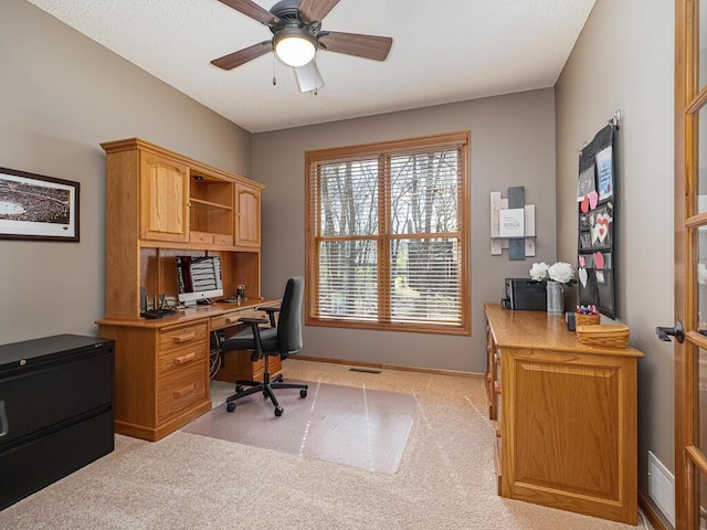 home office featuring a ceiling fan, baseboards, light colored carpet, and visible vents