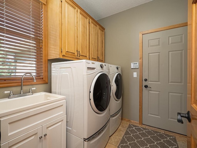 clothes washing area with cabinet space, a sink, separate washer and dryer, a textured ceiling, and light tile patterned floors