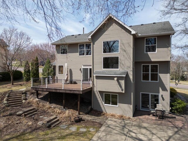back of property featuring a patio, a shingled roof, and a deck