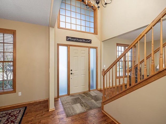 entryway with baseboards, a notable chandelier, wood finished floors, and stairway