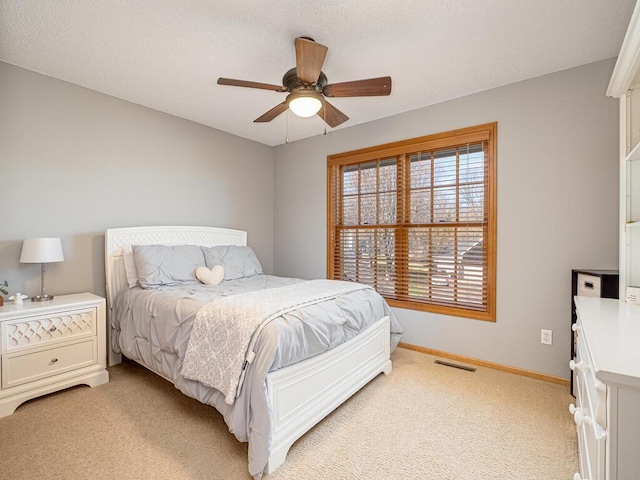 bedroom featuring light colored carpet, baseboards, ceiling fan, and visible vents