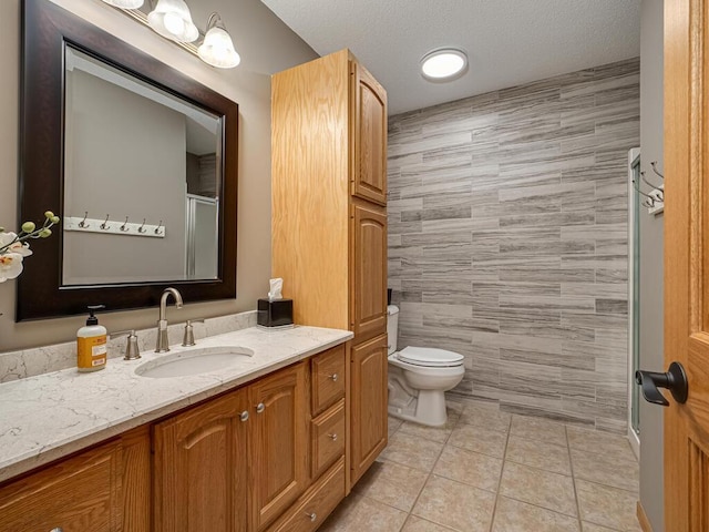 full bathroom featuring tile walls, a shower stall, vanity, tile patterned floors, and toilet