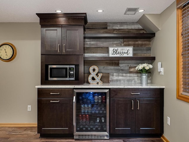 bar with stainless steel microwave, baseboards, wood finished floors, wine cooler, and a bar