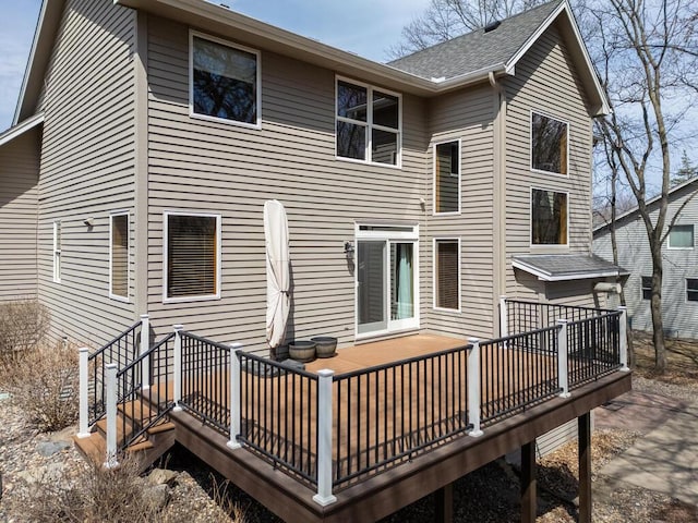 rear view of property featuring a shingled roof and a deck