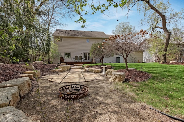 rear view of property with a lawn, a patio area, and an outdoor fire pit