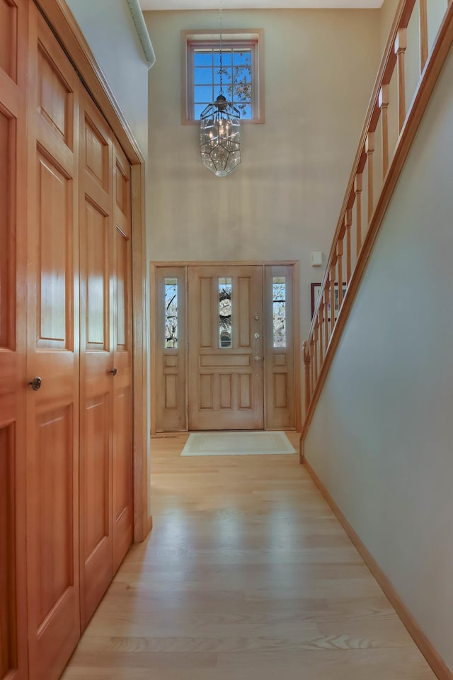 foyer featuring stairway, a healthy amount of sunlight, wood finished floors, and a notable chandelier