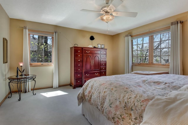 carpeted bedroom featuring baseboards, multiple windows, and a ceiling fan