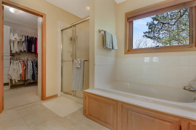 bathroom featuring a stall shower, a bath, and a spacious closet