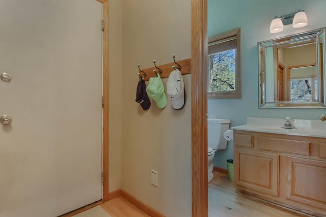 bathroom featuring toilet, baseboards, wood finished floors, and vanity