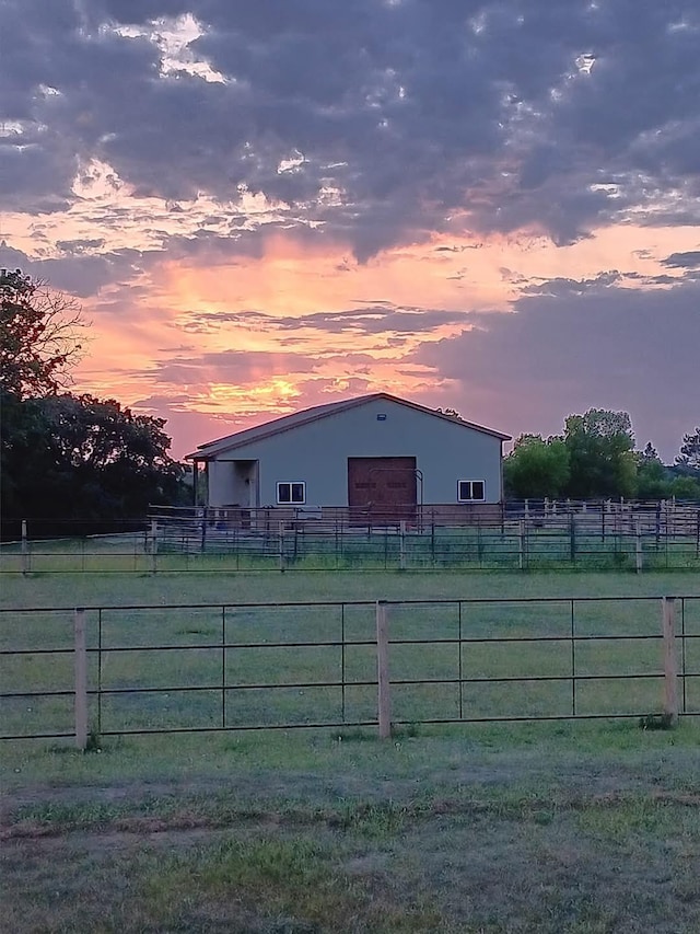 view of pole building with fence and a rural view