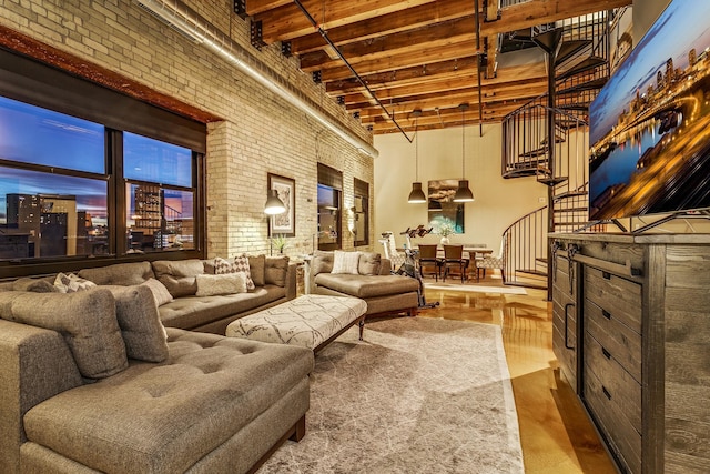406 Wacouta St Unit 707, Saint Paul, MN 55101 - living room featuring wood finished floors, brick wall, beamed ceiling, a high ceiling, and stairway