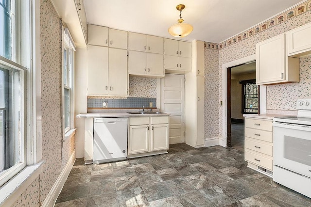 kitchen featuring white appliances, wallpapered walls, a sink, and light countertops