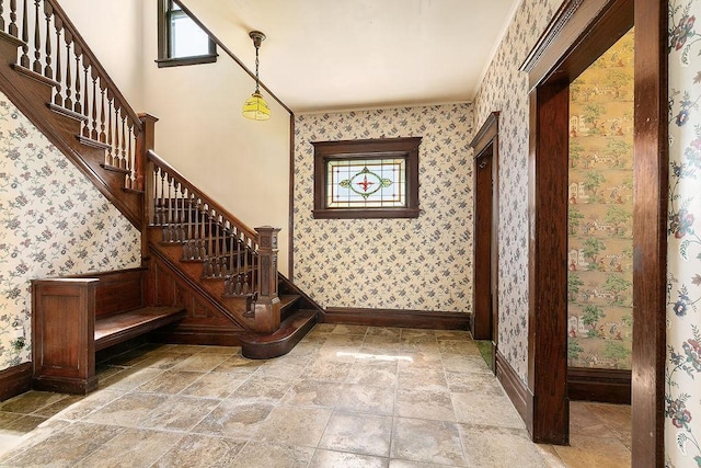 interior space featuring a healthy amount of sunlight, baseboards, wallpapered walls, and stone finish flooring