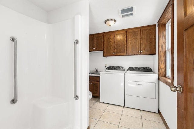 clothes washing area with visible vents, cabinet space, light tile patterned floors, a sink, and separate washer and dryer