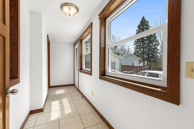 hall featuring light tile patterned flooring and baseboards