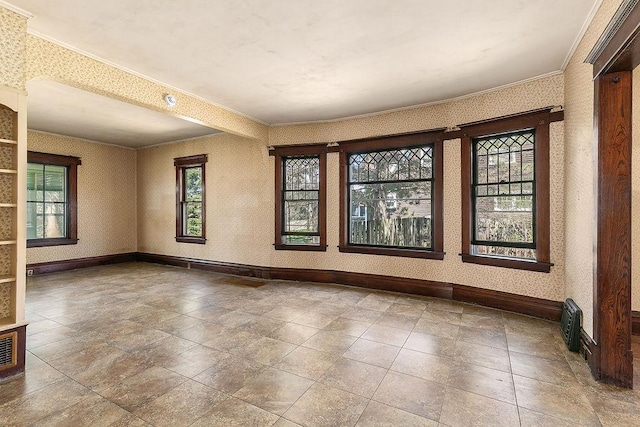 spare room with crown molding, baseboards, and wallpapered walls