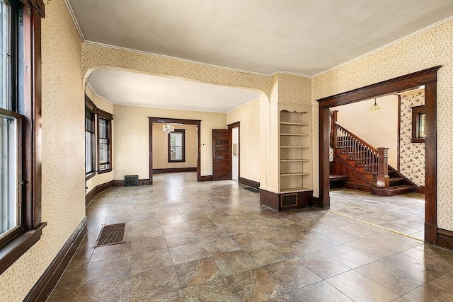 entryway with arched walkways, wallpapered walls, visible vents, and a healthy amount of sunlight