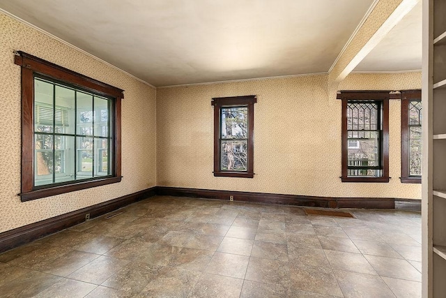 spare room featuring crown molding, baseboards, stone finish flooring, and wallpapered walls