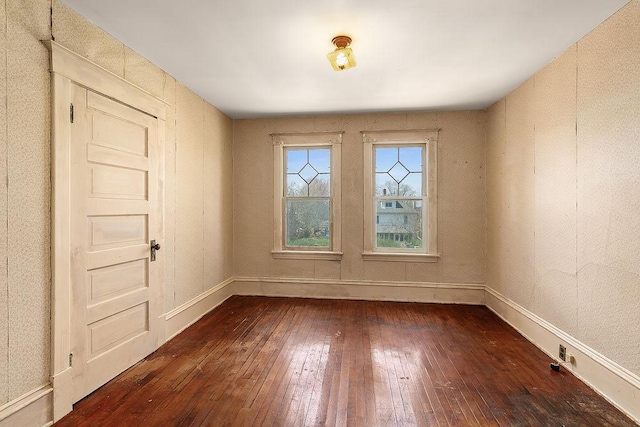 unfurnished room featuring baseboards and dark wood finished floors