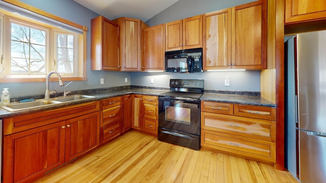 11544 Lake Eunice Rd, Detroit Lakes, MN 56501 - kitchen with black appliances, a sink, light wood-type flooring, dark countertops, and vaulted ceiling