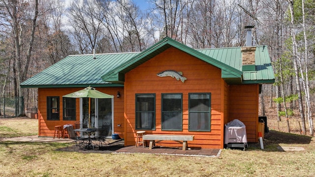 rear view of house featuring a lawn, metal roof, and a patio area