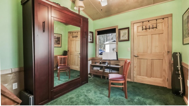 interior space with dark carpet, wainscoting, ceiling fan, and vaulted ceiling
