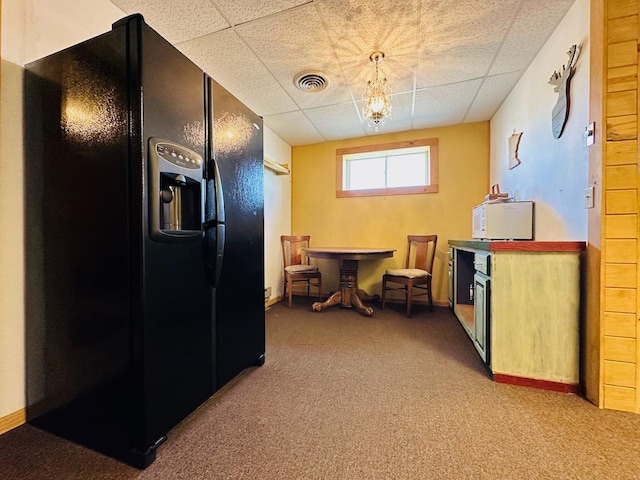 kitchen featuring light colored carpet, black refrigerator with ice dispenser, a drop ceiling, white microwave, and visible vents
