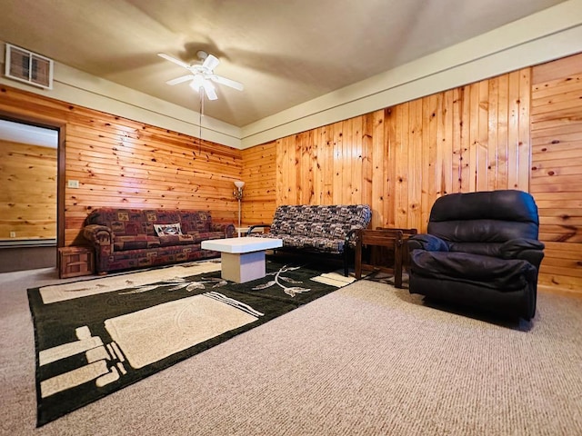 carpeted living area featuring wooden walls, a ceiling fan, and visible vents