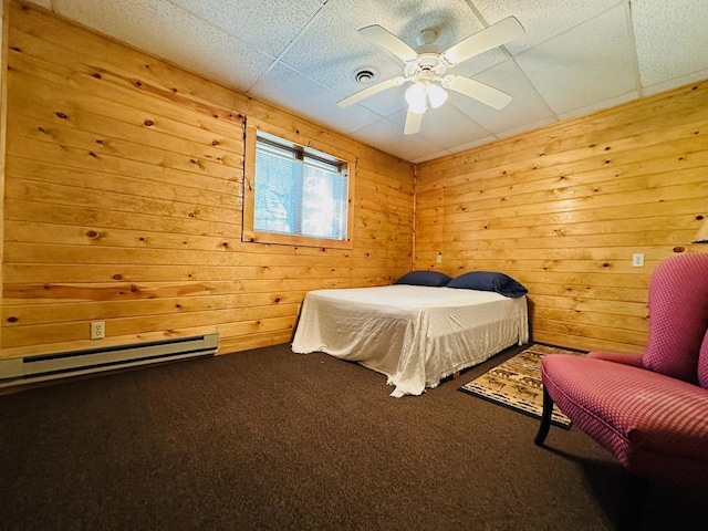 bedroom with wooden walls, a baseboard heating unit, and carpet