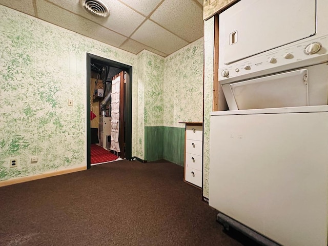 laundry room with laundry area, stacked washer / dryer, baseboards, carpet, and wallpapered walls